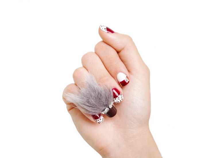 Hand with furry nails featuring red and white polish and a fluffy gray decoration showcasing the furry nails trend.