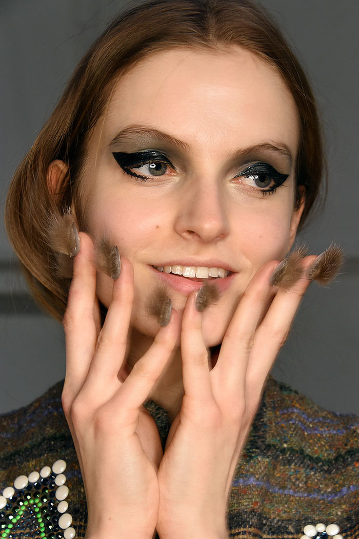 Close-up of a woman smiling, showcasing furry nails as the latest hairiest trend in nail fashion.