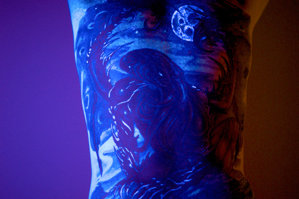 Glow in the dark tattoo of a celestial scene, vividly visible under black light.