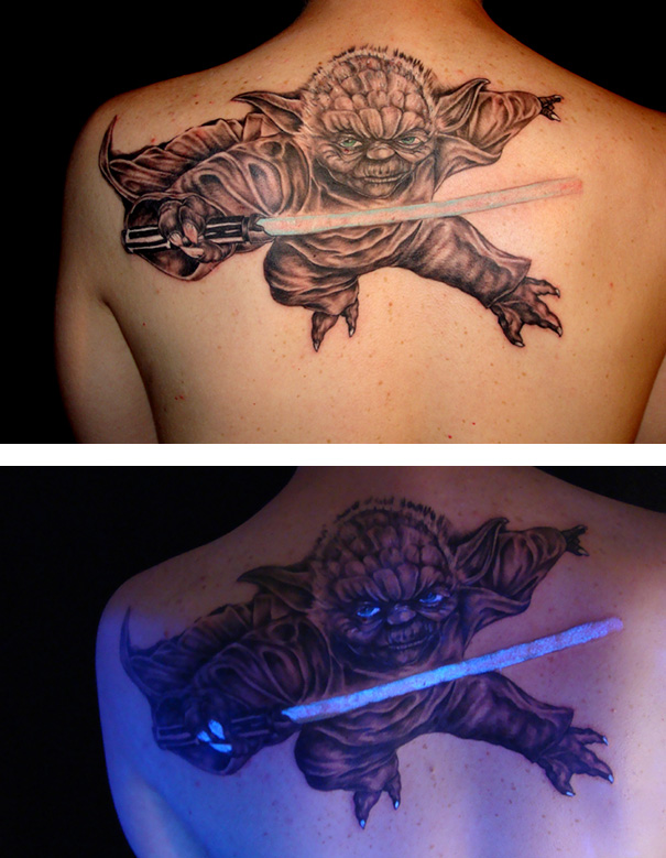 Glow in the dark tattoo of a character with a lightsaber, visible under black light on a person's shoulder.