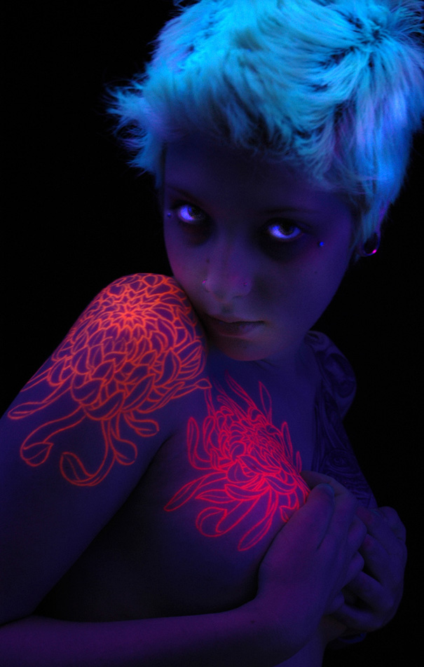 Person with glow in the dark tattoos on shoulder, visible under black light.