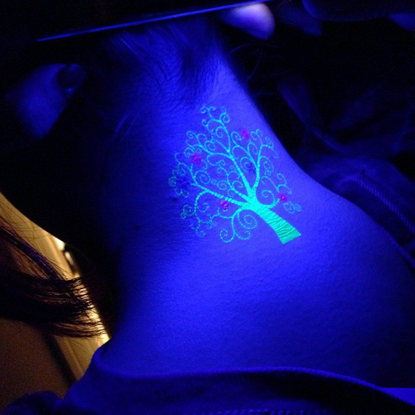 Glow in the dark tree tattoo on neck, illuminated under black light.