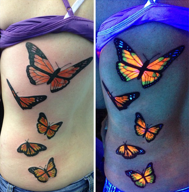 Butterfly glow in the dark tattoos on a back, visible under black light.