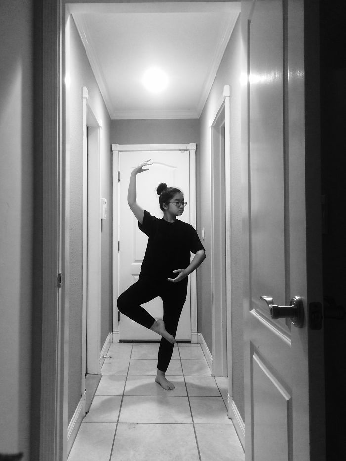 Young ballet dancer practicing a pose in a hallway.