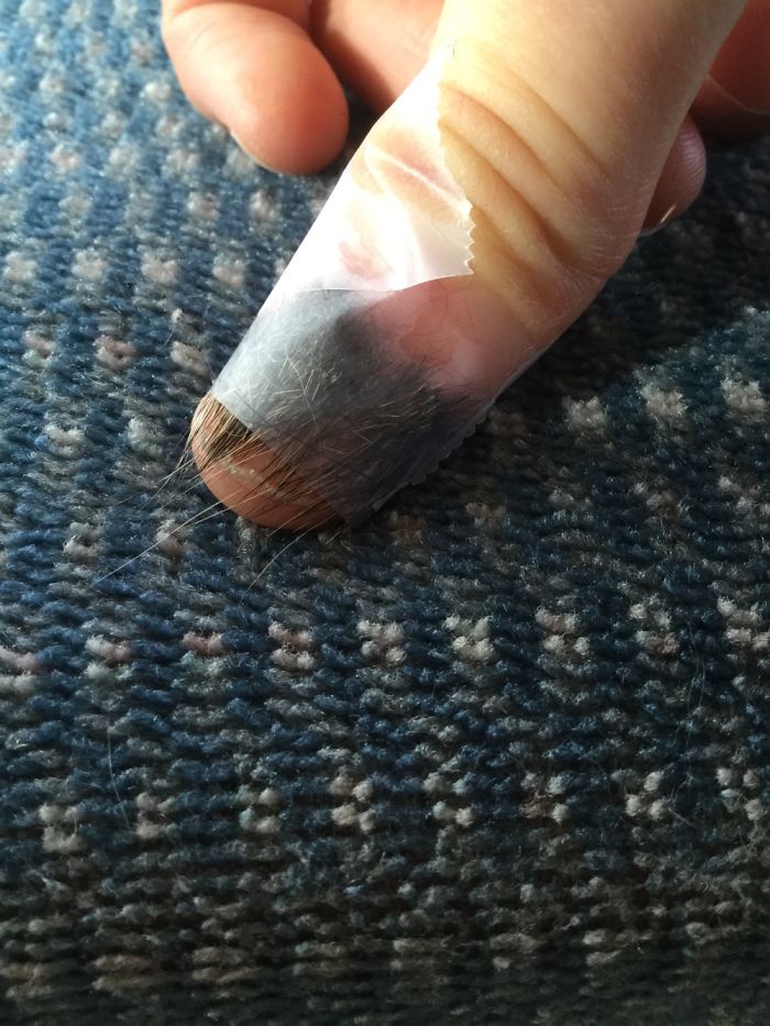 Close-up of a thumb with furry nails covered in tape, showcasing the hairy trend in nail art.