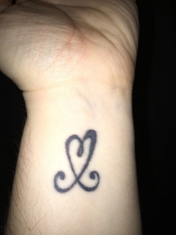 Minimalist tattoo of a stylized heart on a wrist.