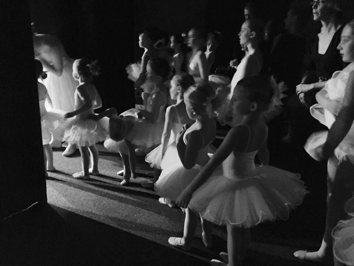 Young ballerinas backstage, preparing in tutus for a performance, capturing the essence of ballet celebration.