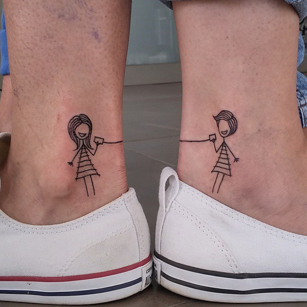 Ankles with matching stick figure tattoos holding hands, symbolizing sister bond.