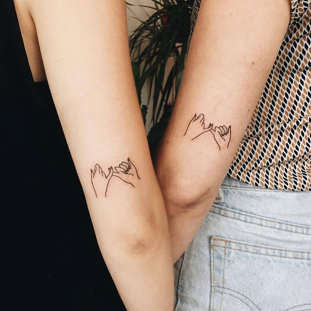 Two forearms with matching sister tattoos featuring pinky promise line art.