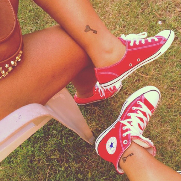 Matching sister tattoos of keys on ankles, wearing red sneakers, symbolizing their bond.