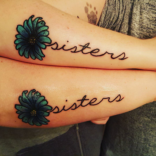 Matching sister tattoos with blue flowers and cursive script on forearms.