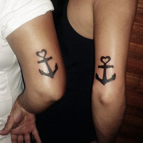 Two arms with matching anchor tattoos, symbolizing sisterly bond and connection.
