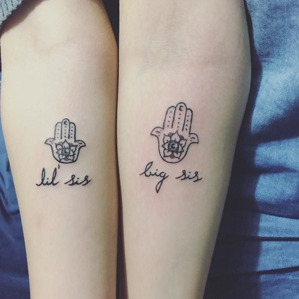 "Matching sister tattoos on forearms, with 'lil sis' and 'big sis' text and hamsa designs."