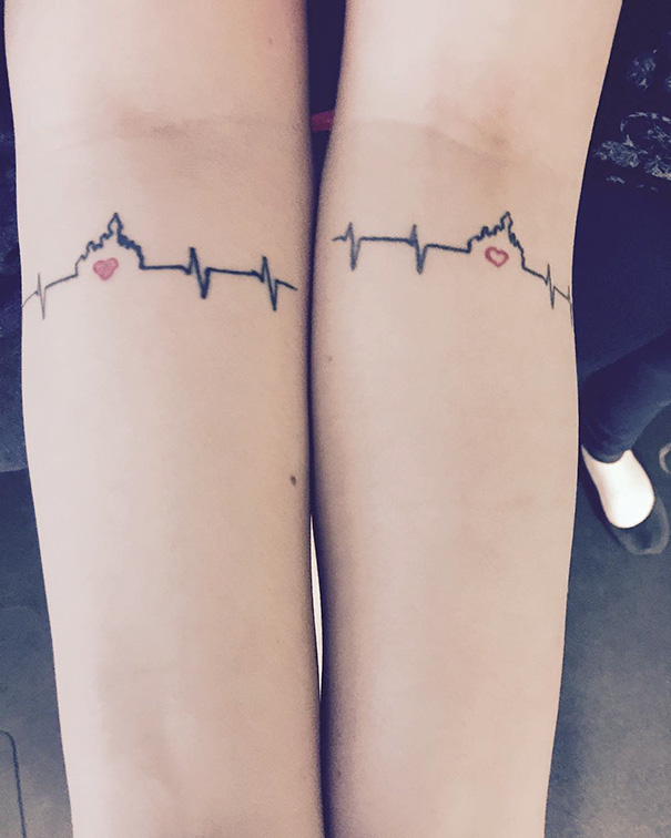 Sister tattoo featuring matching heart and heartbeat design on forearms.