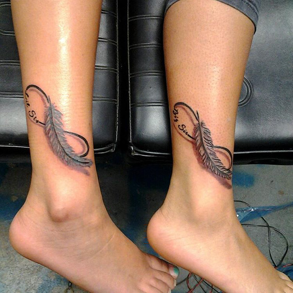Matching sister tattoos with infinity symbols and feathers on ankles symbolize their bond.