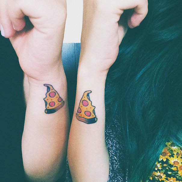 Two wrists with matching pizza slice sister tattoos, symbolizing a strong bond.