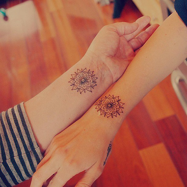 Matching sister tattoos on wrists featuring intricate mandala designs, symbolizing a strong sibling bond.
