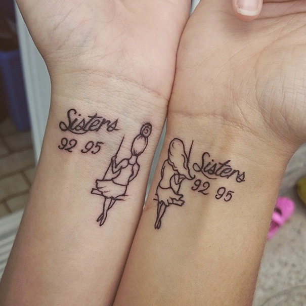 Two wrists with matching sister tattoos showing "Sisters" text and years 92, 95 in black ink.