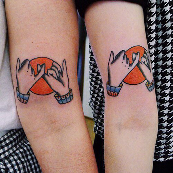Matching sister tattoos of linked pinky fingers over a red circle.