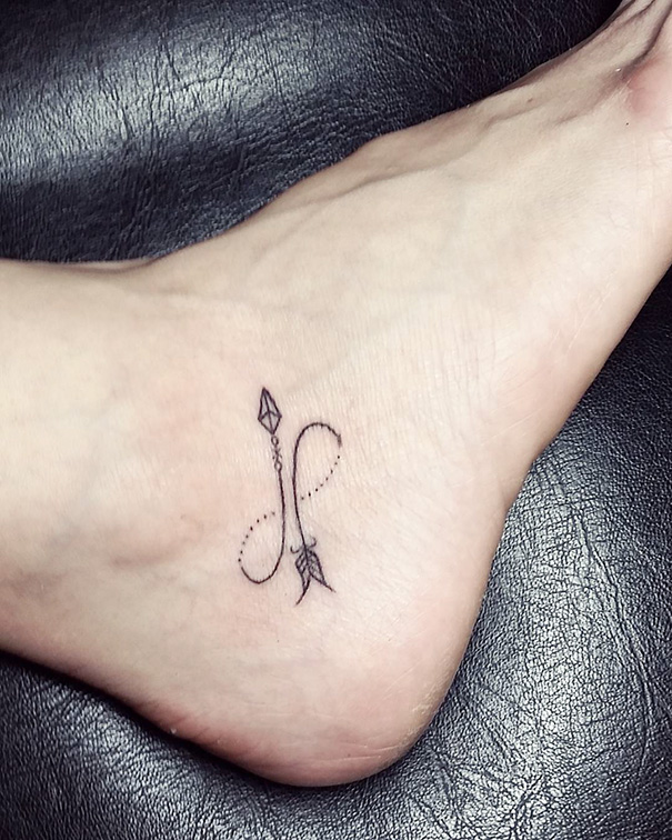 Minimalist tattoo featuring an arrow with intricate line work on a foot.