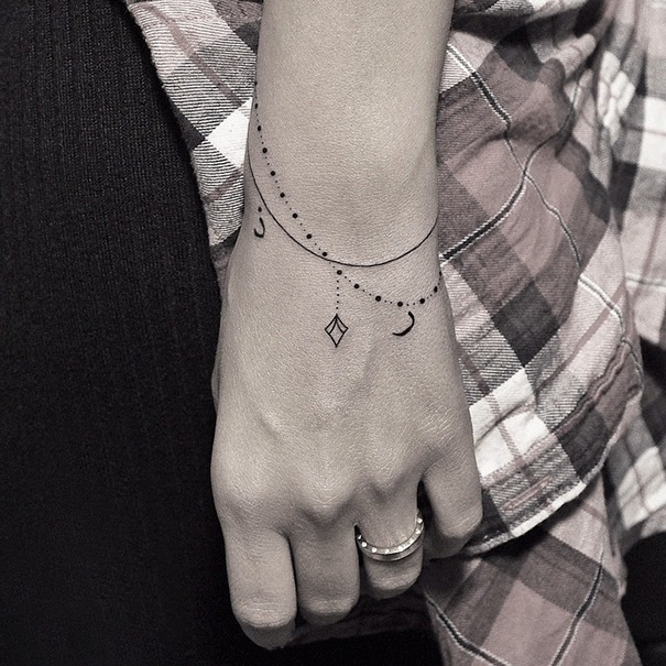 Minimalist tattoo with dots, moons, and diamond shapes on a wrist, showcasing subtle ink design.