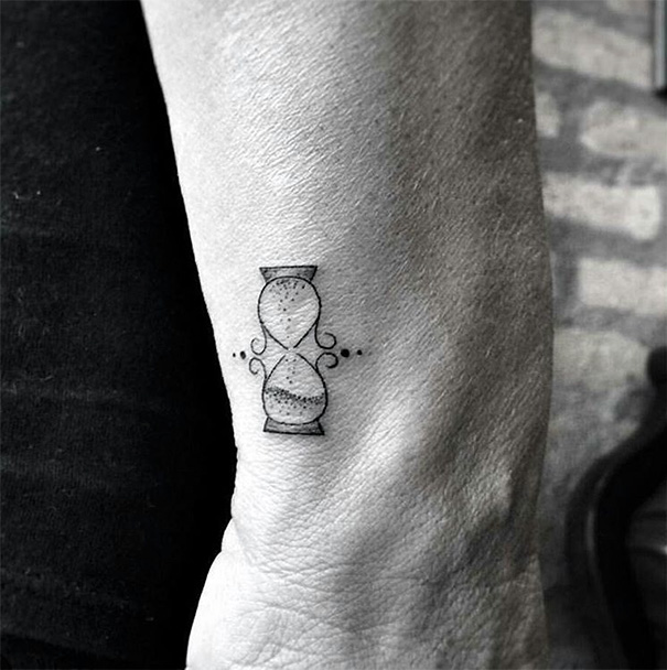 Minimalist tattoo of a small hourglass on the forearm, showcasing simple and elegant design inspiration.
