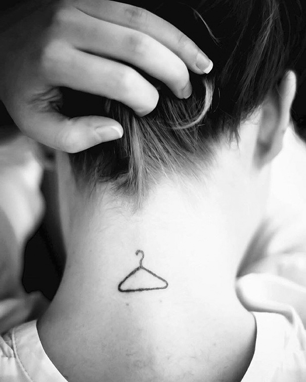 Minimalist tattoo of a hanger inked on the back of a person's neck.