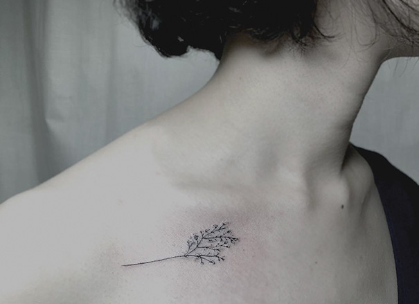 Minimalist tattoo of a delicate branch on a person's shoulder, exemplifying subtle and inspiring ink designs.