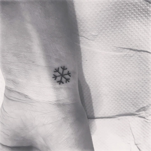 Minimalist snowflake tattoo on a wrist, showcasing simple ink design inspiration.