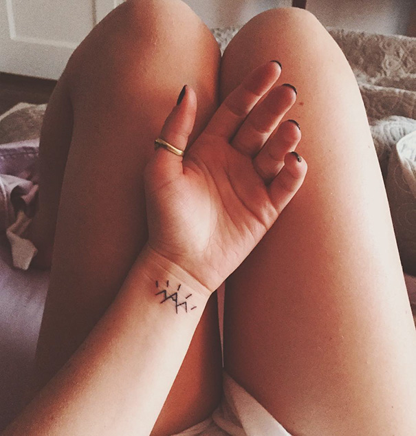 Minimalist tattoo on a person's wrist, featuring a simple design with line elements.