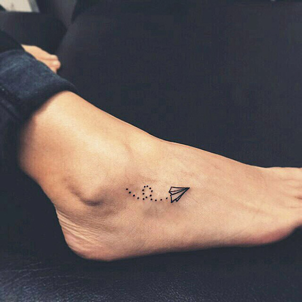 Minimalist tattoo of a paper airplane on a person's foot.