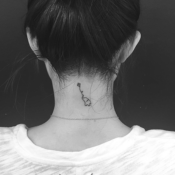 Minimalist tattoo of a small abstract design on the back of a woman's neck.