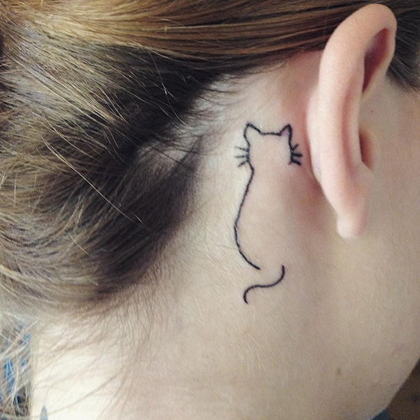 Minimalist tattoo of a cat outline inked behind the ear.