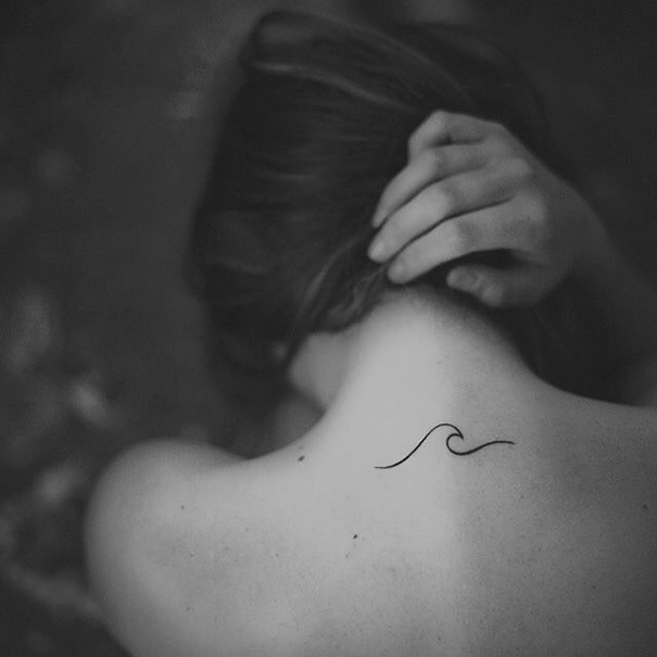 Minimalist tattoo of a wave on the back of a woman's neck, showcasing simple and elegant design.