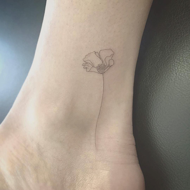 Minimalist tattoo of a delicate flower on the ankle.
