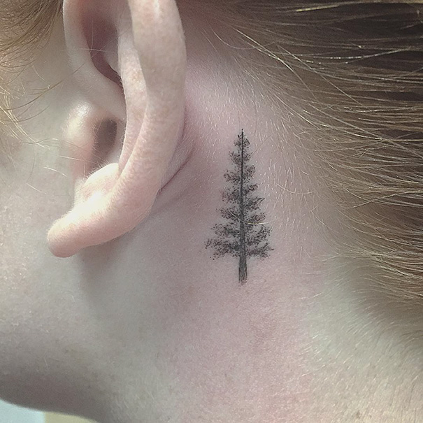 Minimalist tree tattoo behind the ear, showcasing simple ink design inspiration.