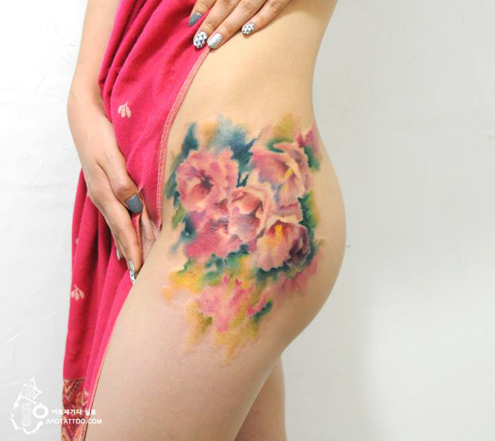 Watercolor-style flower tattoo on a person's hip, resembling a painted artwork. Watercolor-style flower tattoo on a person's hip, resembling a painted artwork.