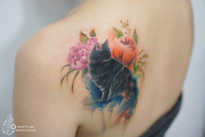 Watercolor flower tattoos with a black cat design on a person's shoulder. Watercolor flower tattoos with a black cat design on a person's shoulder.