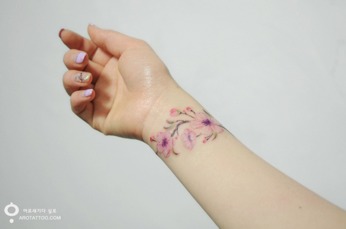 Watercolor-style flower tattoo on forearm, resembling a delicate painting. Watercolor-style flower tattoo on forearm, resembling a delicate painting.