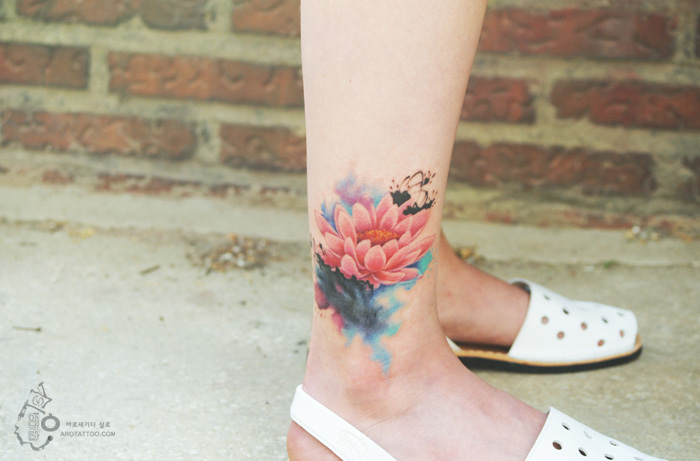 Watercolor-style flower tattoo on ankle, resembling painted artwork against brick background. Watercolor-style flower tattoo on ankle, resembling painted artwork against brick background.