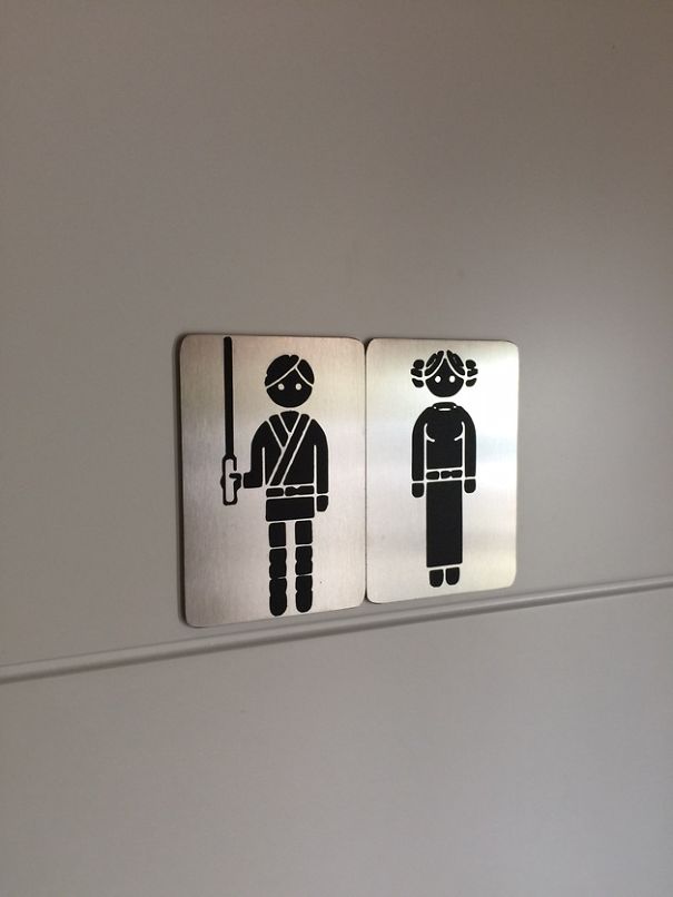 Funny bathroom signs with playful characters resembling sci-fi roles, adding humor to restroom entries.