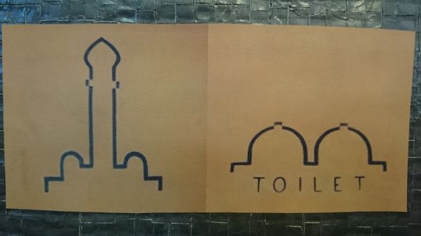 Funny bathroom signs featuring creative illustrations for toilets on a textured wall.