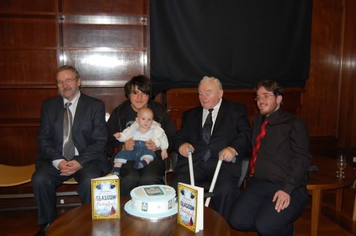 Family members gathered around a table with a cake, showing kids as copy-paste versions of their parents.
