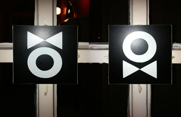 Funny bathroom signs with abstract symbols on black backgrounds.