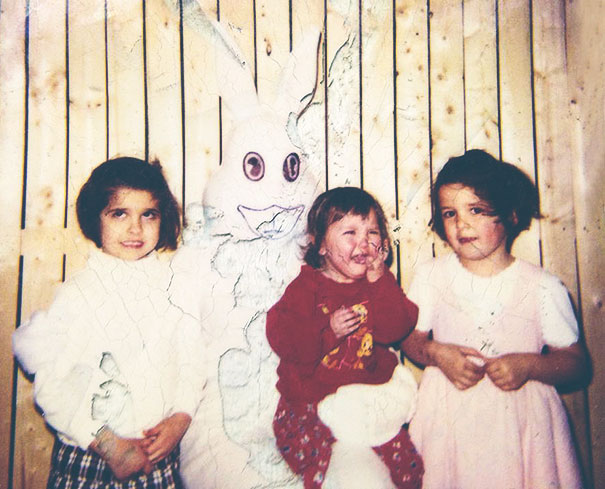 Three children with a vintage Easter Bunny, looking unsettling, in a wooden photo setting.