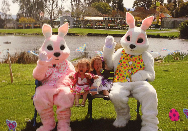 Children sitting with vintage Easter bunnies by a lake, looking distressed.