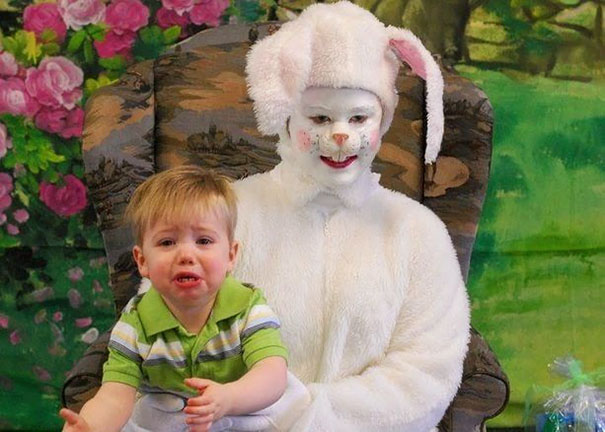 Child crying on lap of person in a creepy vintage Easter bunny costume.