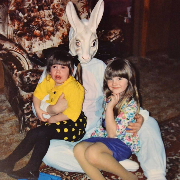 Two children sitting with a vintage Easter Bunny in unsettling costume, one smiling, the other crying.
