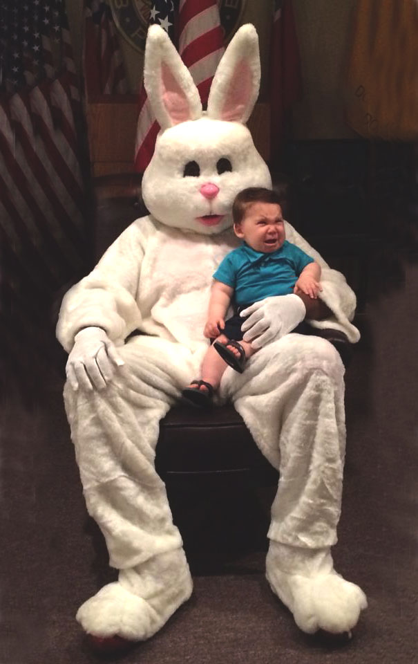 A child sits on a vintage Easter Bunny's lap, appearing frightened, in this unsettling photo.