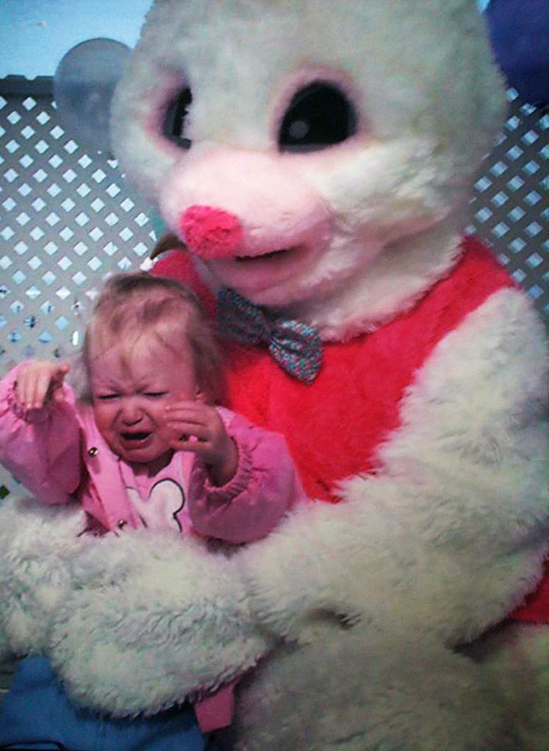 Child crying while sitting on a vintage Easter bunny's lap, evoking a sense of unease.